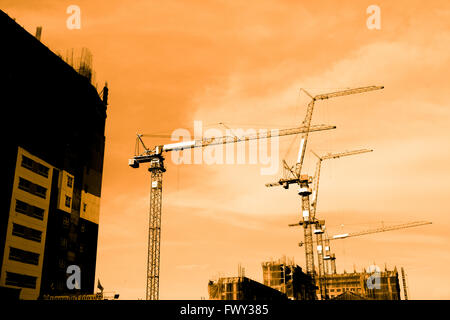 Silhouette of construction workers on scaffold working under a hot sun Stock Photo