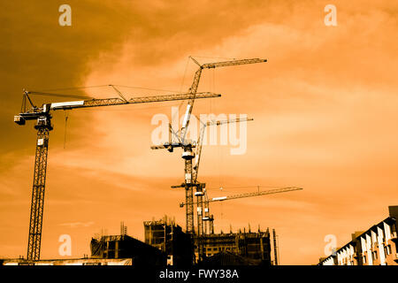 Silhouette of construction workers on scaffold working under a hot sun Stock Photo