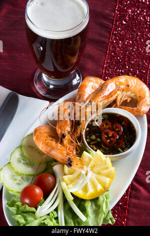 An English pub/bar dish of Sautéed King Prawns with Sweet Chili and Tamarind dip and a fresh side salad. And a glass of beer/ale Stock Photo