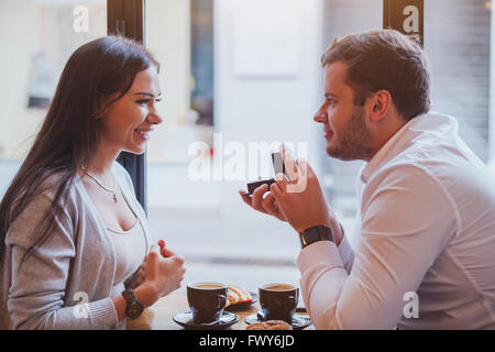 proposal, engagement concept, happy couple in restaurant, man offers the ring, marry me