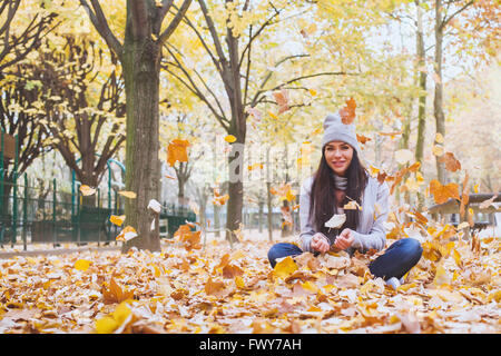 autumn park, beautiful smiling woman and falling yellow leaves