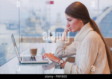 woman using laptop in modern cafe interior, free wifi, checking email Stock Photo