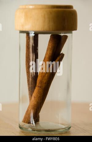 Cinnamon in the glass jar on wooden table, white background. Stock Photo
