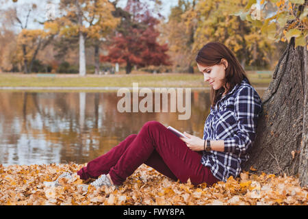 literature, young beautiful woman reading book in autumn park near the lake Stock Photo