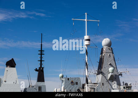 The mast of HMS M33 rises in front of HMS Dauntless (D33) in the Royal Naval Dockyard, Portsmouth. Stock Photo