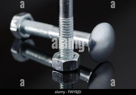 Two metal screws with nice reflection on black background. Stock Photo