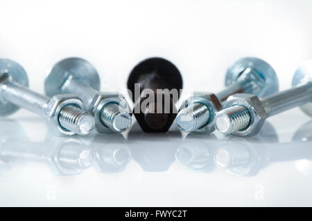 One old rusty screw among four new screws. Stock Photo