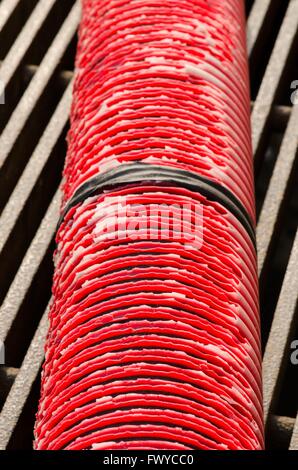Old red pipe with black tape connection on grate. Stock Photo