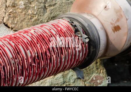 Old red pipe with black tape connection on grate. Stock Photo