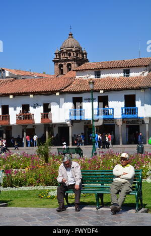 Two old men take a break on a park bench in the Plaza de Armas in Cusco Peru. Stock Photo