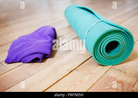 Mat for yoga rolled-up on wooden floor Stock Photo