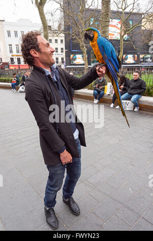 Performer with a parrot at Leicester Square Garden, London England United Kingdom UK Stock Photo