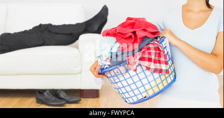 Composite image of brunette holding a basket full of laundry Stock Photo