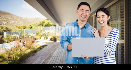 Composite image of portrait of couple using laptop Stock Photo