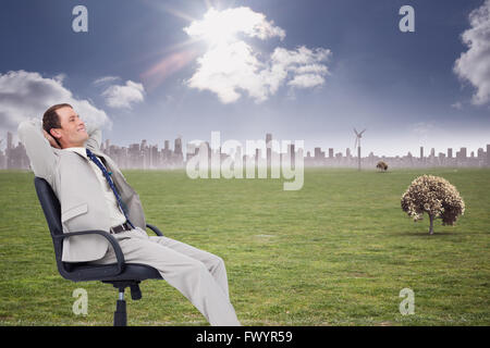 Composite image of side view of businessman leaning back in his chair Stock Photo
