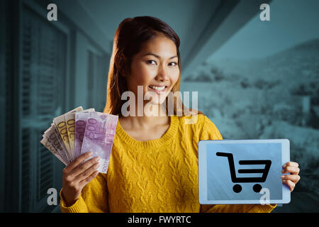 Composite image of smiling asian woman showing tablet and bank notes Stock Photo