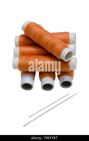 Seven reels of orange thread and two needles. Stock Photo