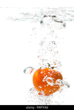Falling tomato into water, air bubbles around. Stock Photo