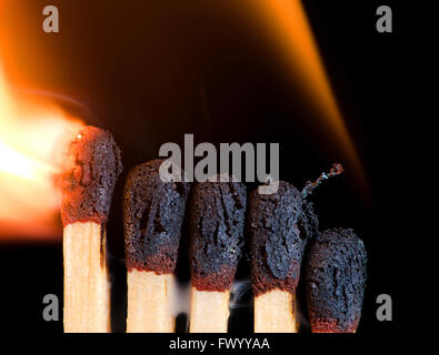 Close-up of five burning matches on black background. Stock Photo