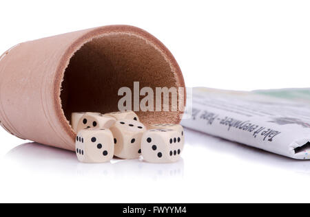 Seven wooden dice on the leather dish and newspaper beside. Stock Photo