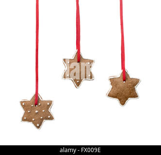 Gingerbread stars hanging on red ribbons against white background. Stock Photo