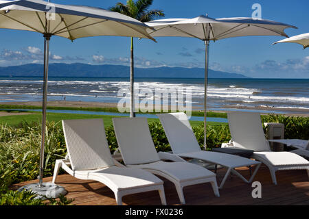 Deck chairs and umbrellas at a resort on the beach with surf Stock Photo