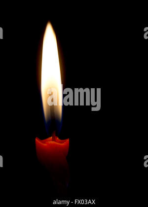 Twisted red candle with genuine large flame on black. Stock Photo
