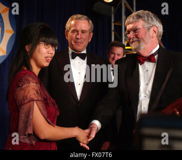 May 21, 2005 - Washington, District of Columbia, United States of America - Washington, DC - May 21, 2005 -- United States President George W. Bush, center, and Nhanny Heil, left, congratulate Chick Herrity, right, as he receives the White House News Photographers Association (WHNPA) ''Lifetime Achievement Award'' at the annual ''Eyes of History'' Gala in Washington, DC on May 21, 2005. Ms. Heil was photographed by Mr. Herrity in Saigon, Vietnam where she was orphaned. The photo of Ms. Heil is one of Mr. Herrity's award winning photos. She lives in the United States with her adoptive p Stock Photo