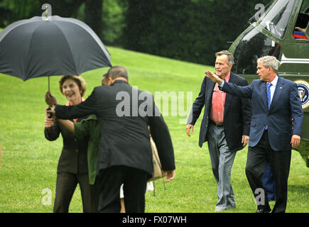 Washington, District of Columbia, USA. 11th May, 2008. Former United States President George H.W. Bush (2nd, R) walks with US President George W. Bush as an aide assists first lady Laura Bush with an umbrella as they arrive at the White House from a weekend at the Crawford, Texas ranch, 11 May 2008 in Washington, DC. Bush, whose daughter Jenna married Henry Hager at the ranch, described the experience as 'spectacular' and 'it's all we could have hoped for'. Credit: Mike Theiler/Pool via CNP © Mike Theiler/CNP/ZUMA Wire/Alamy Live News Stock Photo