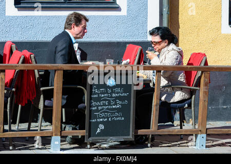 Simrishamn, Sweden - April 1, 2016: Two persons eat outside a restaurant. The female is drinking from a wine glass. A small menu Stock Photo
