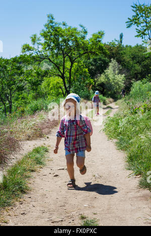 Little sisters (3 and 4 years) go hiking with backpacks. Selective focus. Stock Photo