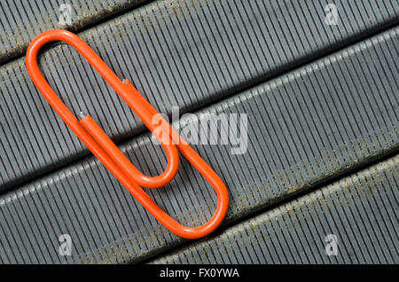 Orange paper clip on staple wire background as symbol of solitude. Stock Photo