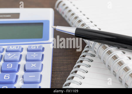 Pen, notepad, and calculator on the wooden table Stock Photo