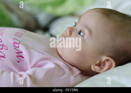 One baby girl sitting on bed Stock Photo