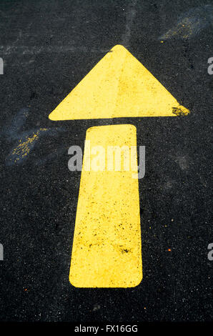 Yellow arrow painted on street to direct traffic Stock Photo