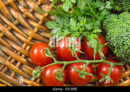 Cherry tomatoes with parsley and broccoli on a wooden plate Stock Photo