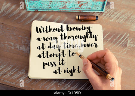 Retro effect and toned image of a woman hand writing on a notebook. Handwritten quote Without knowing a way thoroughly at day time, never attempt to pass it at night as inspirational concept image Stock Photo