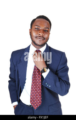 A young black business man standing in a blue suit and tie, fixing his tie for white background. Stock Photo