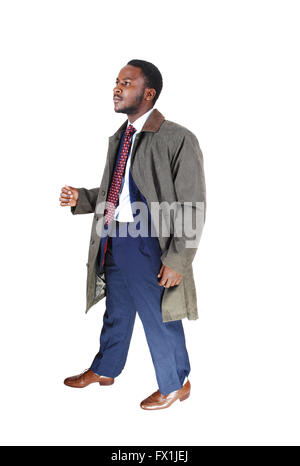 A young African American man in a blue suit and tie with a grey coat walking isolated for white background. Stock Photo