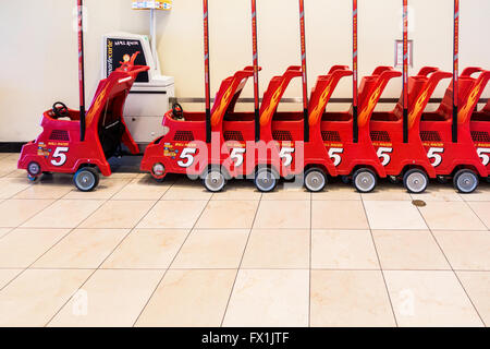 Red rental child strollers lined up in a shopping mall in Oklahoma City, Oklahoma, USA. Side view. Stock Photo