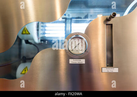 Pressure indicator and gas flow indicator in an refinement machine system. Fluorescent lamps and high voltage labels inside. Wat Stock Photo