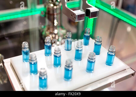 Robotic mechanical arm is manipulating chemical tubes full with blue substance in a medical laboratory during a test. Stock Photo