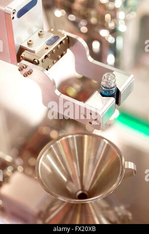 Robotic mechanical arm is pouring chemical tubes full with blue substance in a medical laboratory during a test. Stock Photo