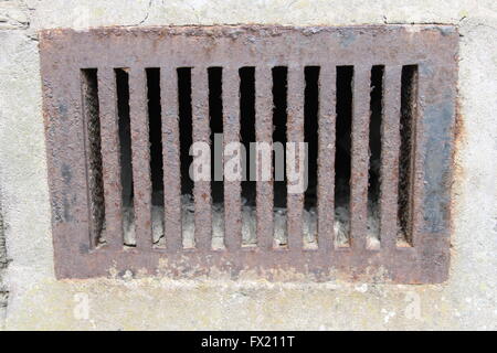 Close up of old, slightly rusty, cast iron grid or air vent in a stone wall. Stock Photo