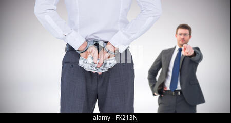 Composite image of businessman in handcuffs holding bribe Stock Photo