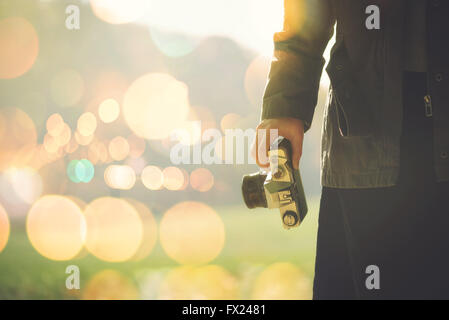 Female photographer shooting outdoors on autumn afternoon sunlight, retro toned image with selective focus Stock Photo