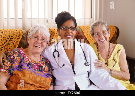 Old people in geriatric hospice: Elderly man and woman hugging an african american doctor, showing a friendly relationship betwe Stock Photo