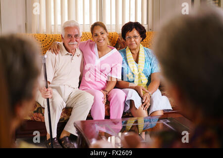 Old people in geriatric hospice: Elderly man and woman hugging a young nurse, showing a friendly relationship between personnel Stock Photo
