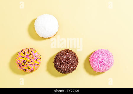 Marshmallow biscuits with colored sugar sprinkles over yellow background Stock Photo