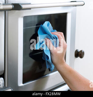 Woman cleaning a oven door with a microfiber cloth. Stock Photo